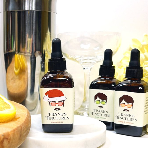 Bottles of Frank's Tinctures with labels featuring cartoon faces on a white surface.