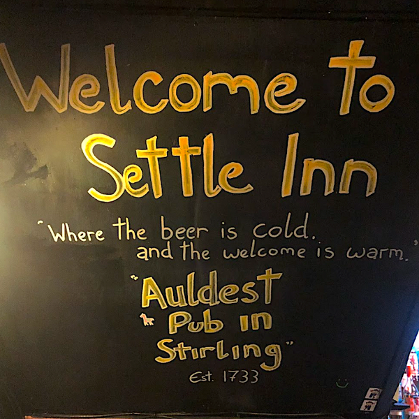 Welcome sign for Settle Inn with gold text on a black background