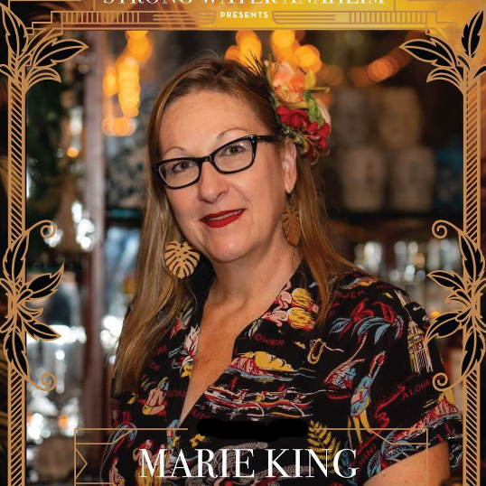 Marie King, Tiki Cocktail God, with floral headpiece in a bar setting, with decorative text overlay.